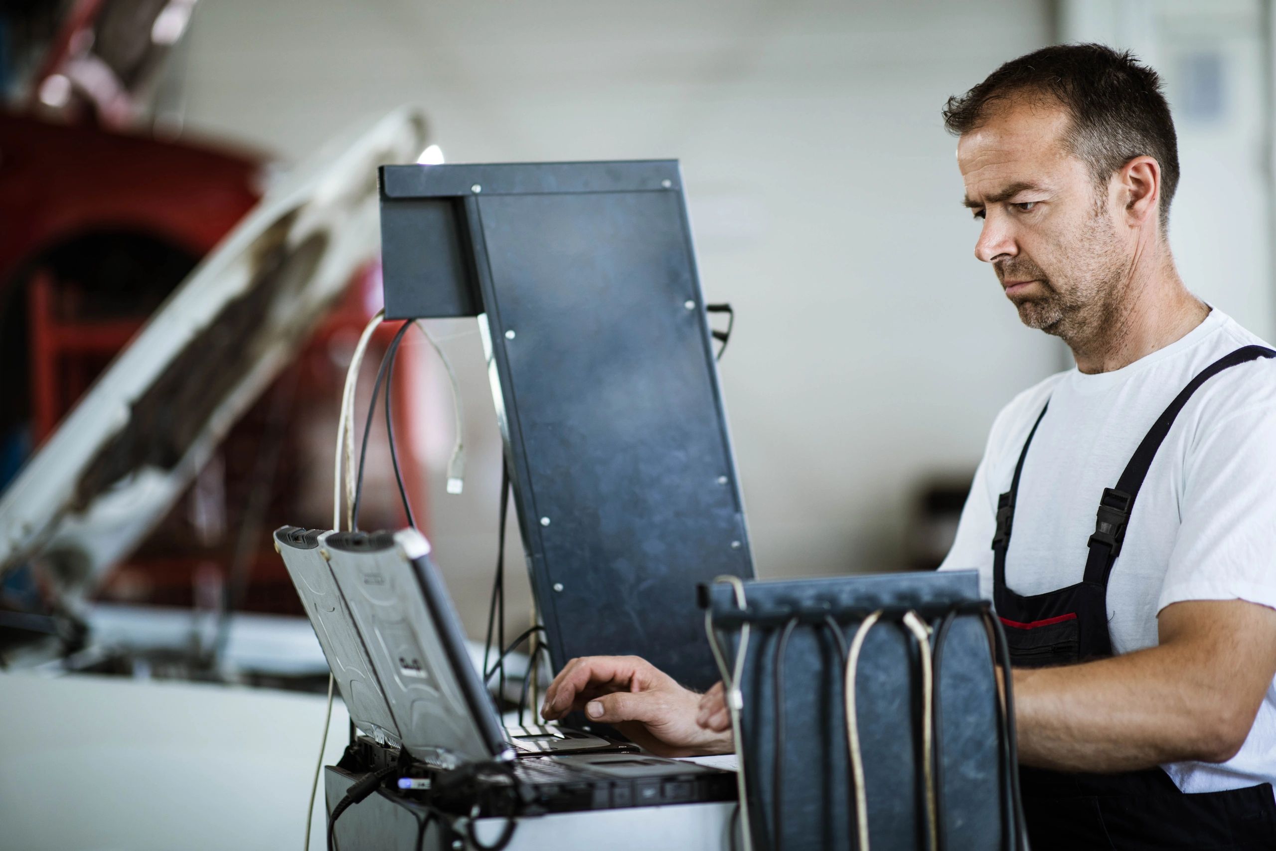Technician using a laptop to run vehicle diagnostics in a modern repair shop