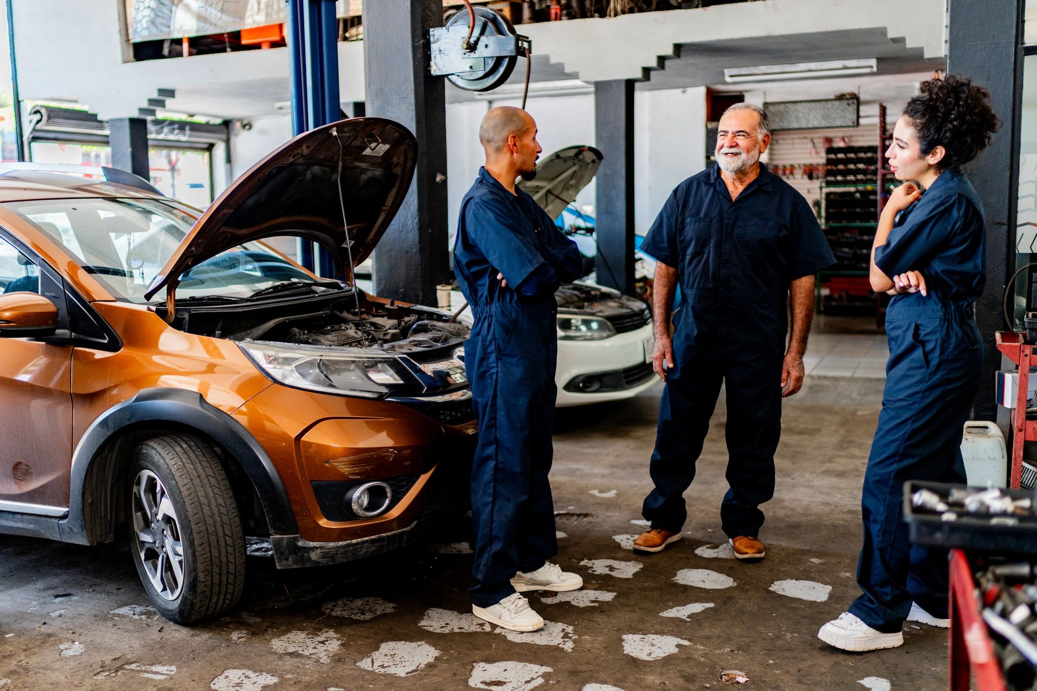 Mechanics discussing a vehicle in a service bay